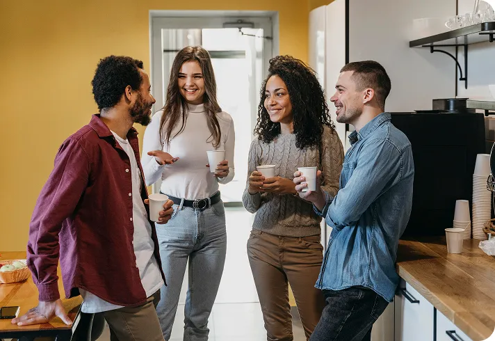Colegas platicando con un café en la cocina de una oficina