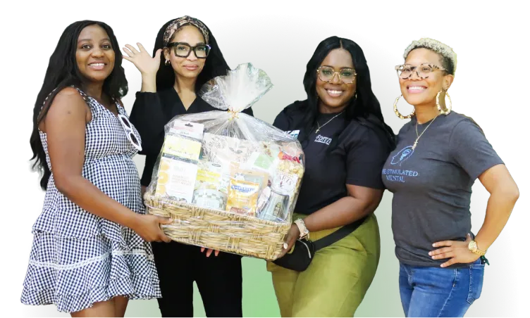 Cuatro mujeres de la comunidad de recuperación de Houston sonriendo y sosteniendo una canasta de regalo