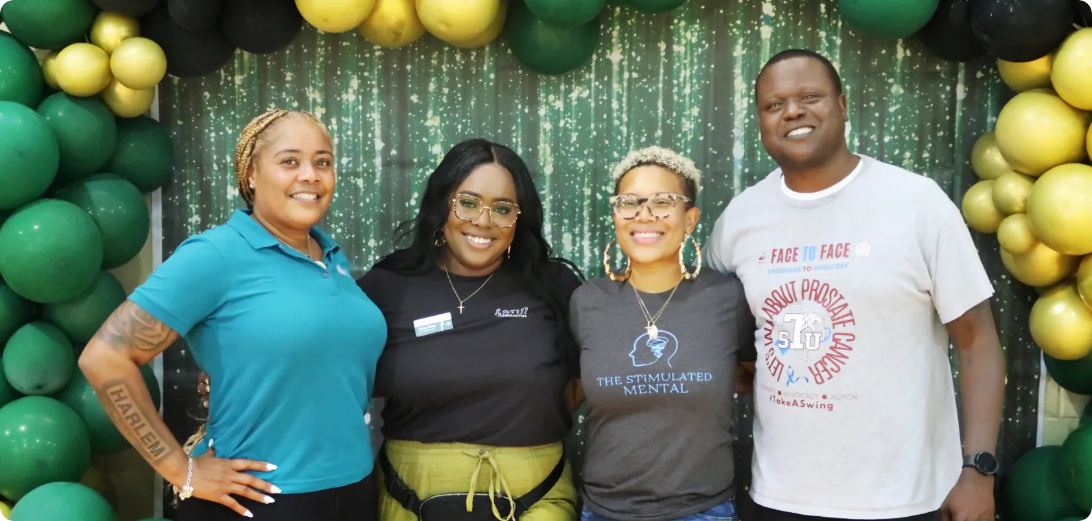 Cuatro líderes de pares de Houston sonriendo juntos frente a una pared de globos verdes y dorados